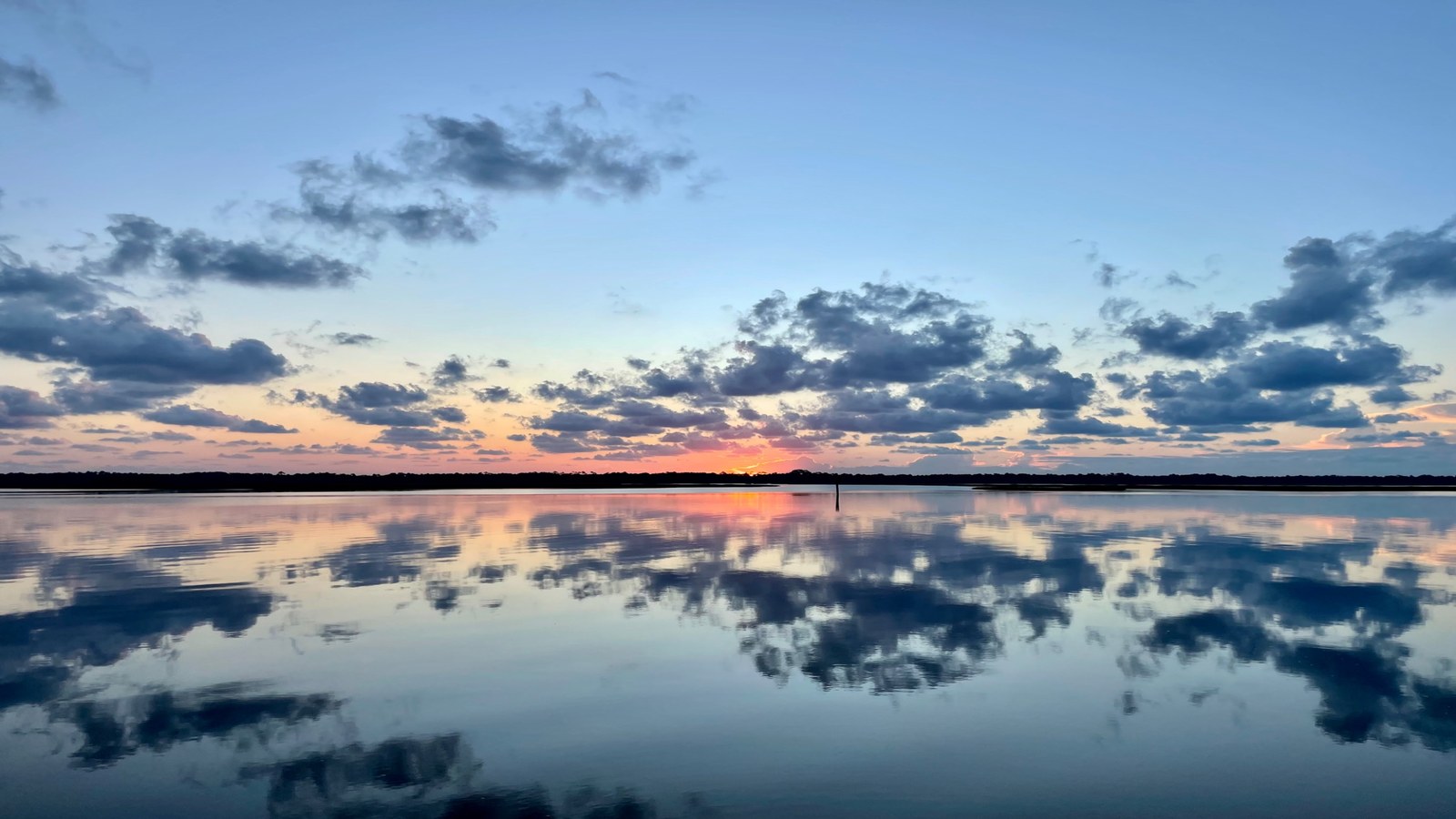 Still water at sunset with clouds reflected on the surface