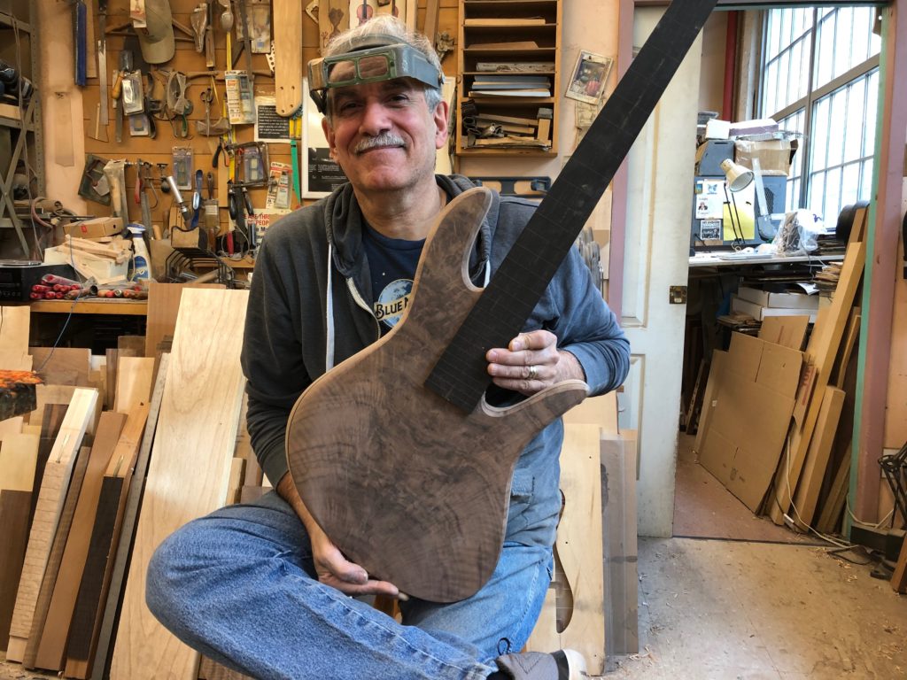 Vinny Fodera holding the completed walnut fretless bass